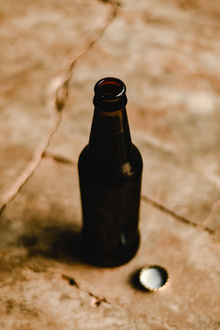 Close-up of an open dark glass beer bottle on a rustic surface in Estonia.